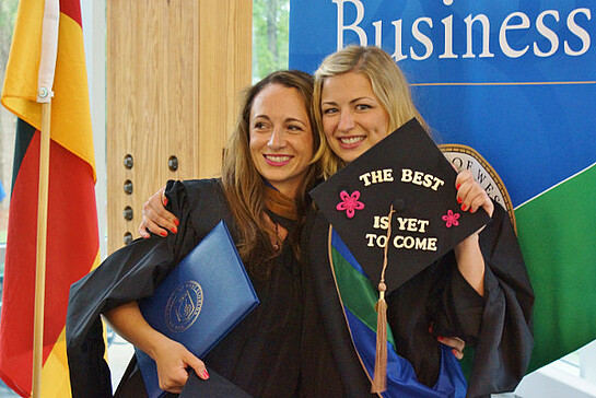Two women in graduate uniform