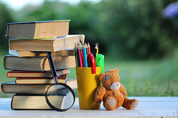 Book stack with magnifying glass and teddy bear