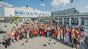 Absolvent*innen werfen ihre Abschlusshüte