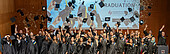 Graduates throw their graduate hats and confetti into the air on stage