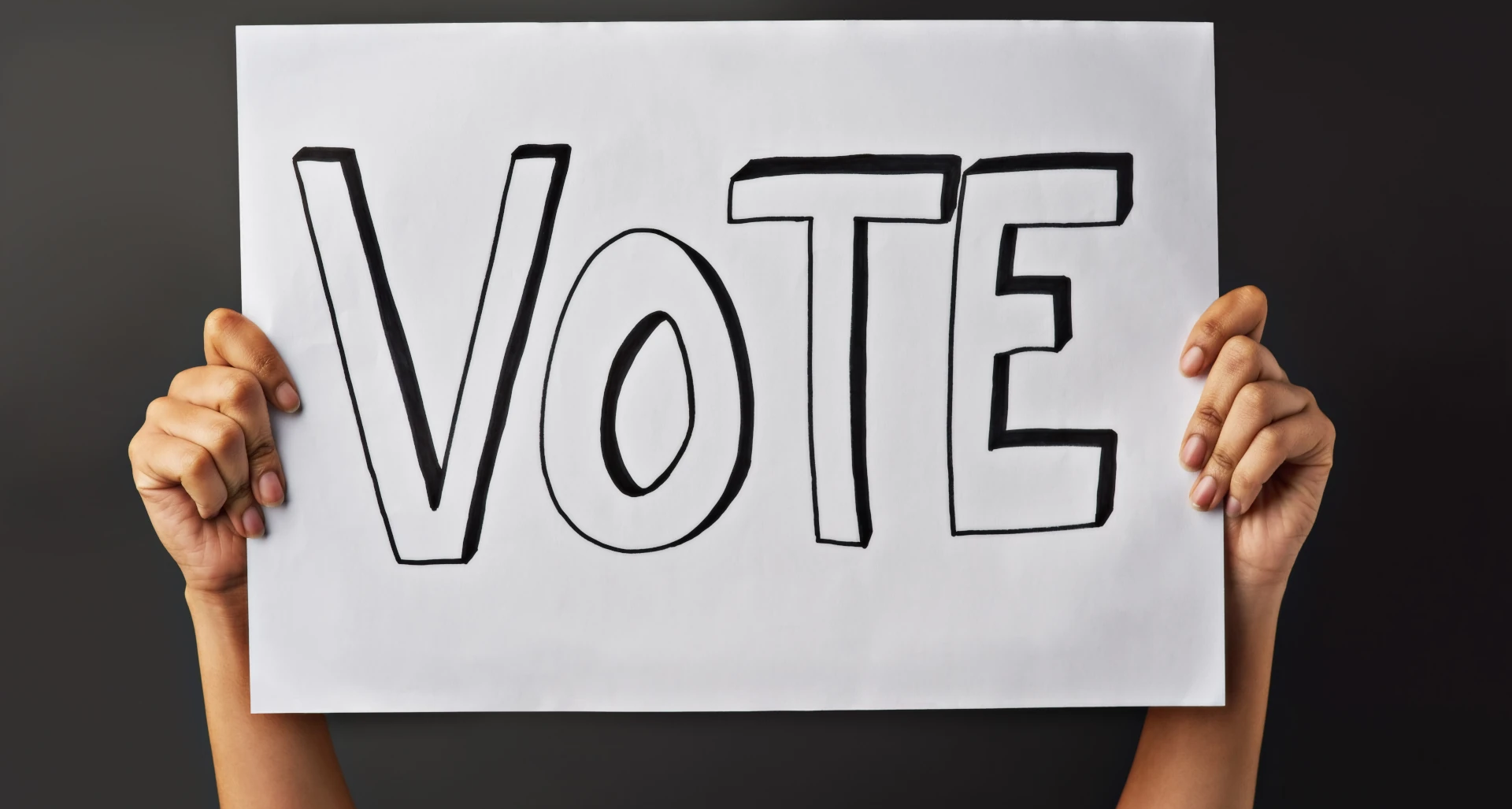 Eine Person hält ein Schild mit "Vote" hoch