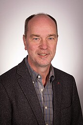 Porträtbild eines älteren Mannes mit grau meliertem Bart und Halbglatze