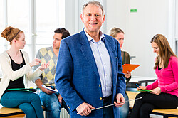 The picture shows a professor standing in front of a group of students