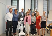 Staatssekretärin Nicole Steingass (rechts neben Pepper) zusammen mit dem Projektteam und der Hochschulleitung