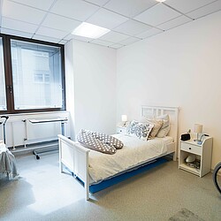 Übungsraum mit Krankenbett, eine Übungspuppe sitze in einem Stuhl neben dem Bett.