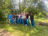 260521_Green Office_Clean-up_Group_photo Group of adults and 2 children in the countryside with bin bags and litter pickers