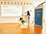 Frau an Rednerpult in Vortragssaal