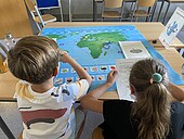 Back view of two children looking at a world map