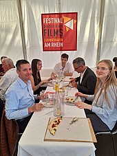 Tisch mit Gästen des Netzwerktreffens beim Essen und Trinken in der Festivallounge.