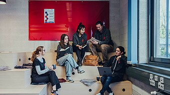 Studierende auf einer Sitztreppe im Kreativraum