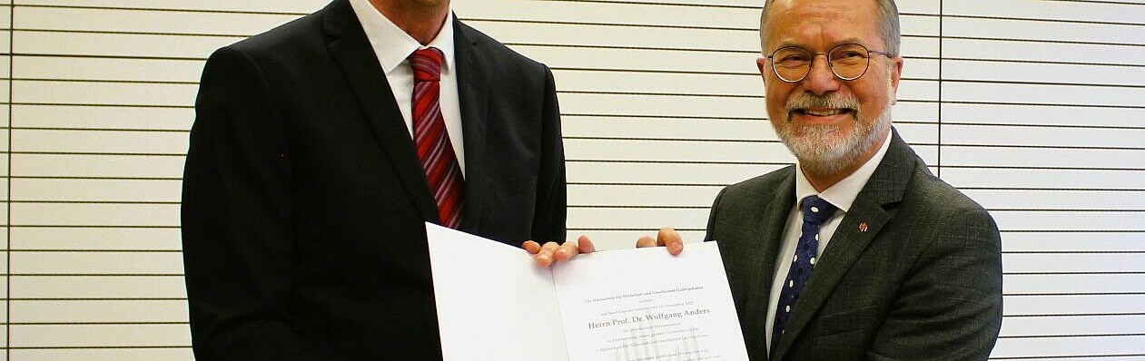Hochschulpräsident Prof. Dr. Gunther Piller (links) überreicht die Urkunde an Ehrensenator Prof. Dr. Wolfgang Anders. (Bild: HWG LU)