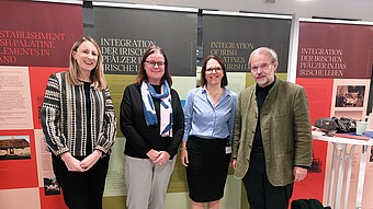 Group photo of the four speakers in front of the poster exhibition