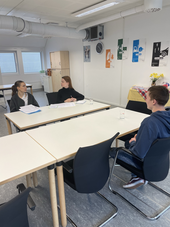 Zwei Personalmanagementstudierende führen ein simuliertes Bewerbungsgespräch mit einem Schüler in einem Unternehmen durch
