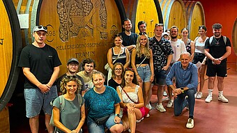 Studierendengruppe vor großem Weinfass