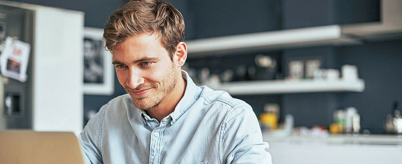 Student sitzt am Schreibtisch zuhause am aufgeklappten Laptop