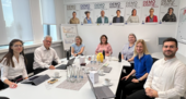 Seven people are sitting around a table, working