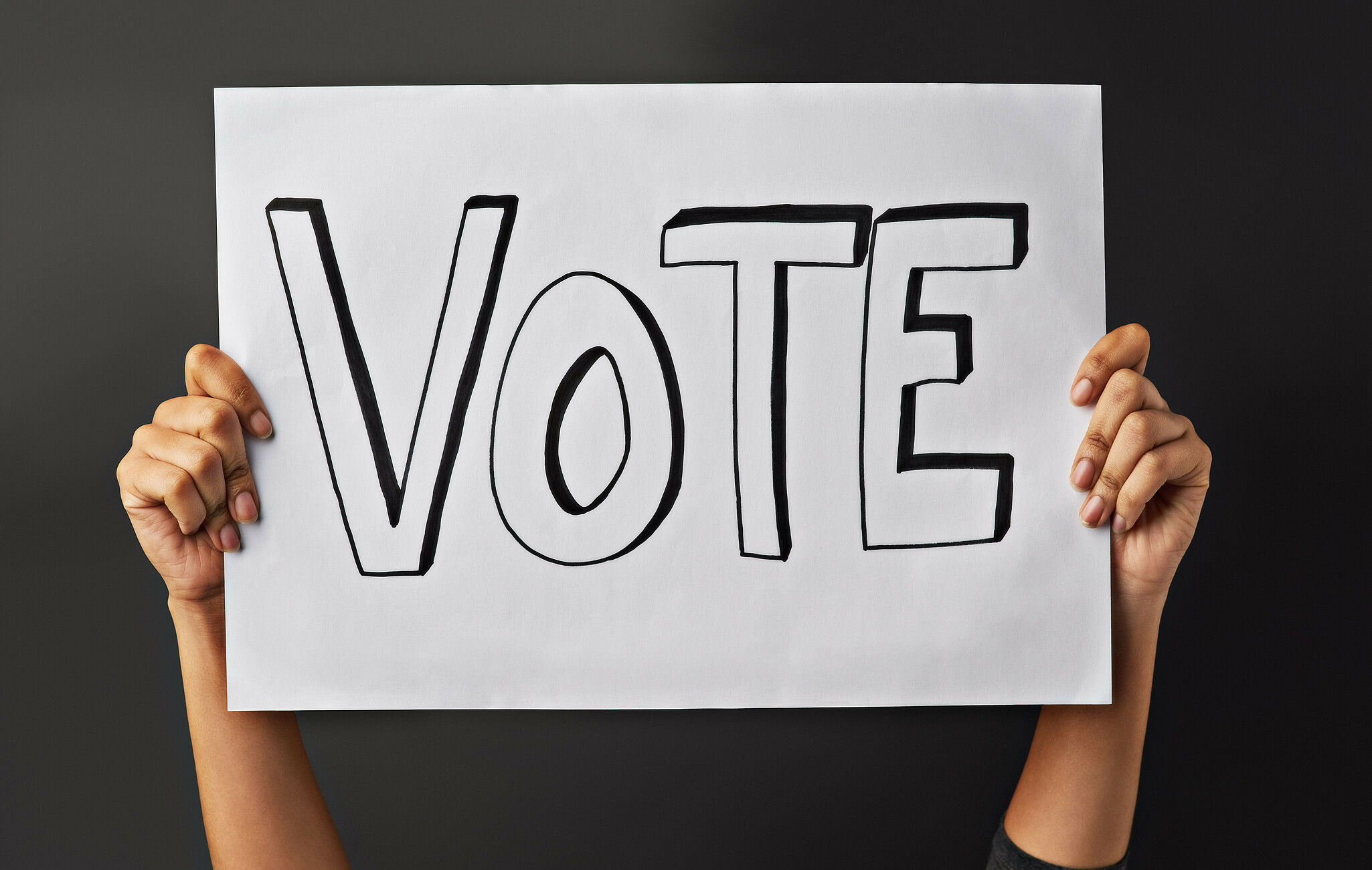 Eine Person hält ein Schild mit "Vote" hoch