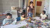 Kinderzukunftsdiplom_Collagen-IBE-2026 Kinder sitzen am Tisch mit zeitschriften, Scheren und Kleber und fertigen Collagen an