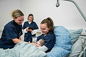 Three midwifery students recreate a scene on the maternity ward with a baby doll